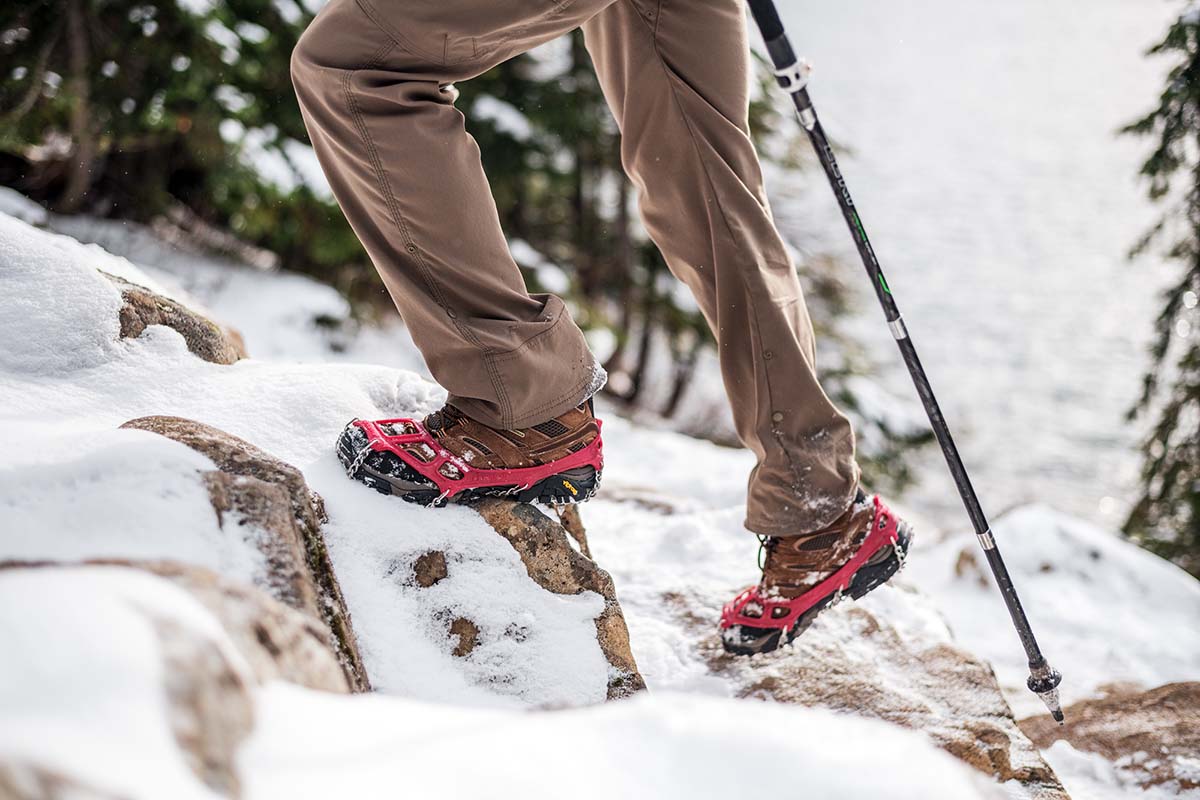 Stepping on snowy rocks with a winter traction device (winter boot)